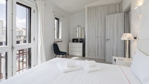 A hotel room with a bed, a desk, a chair, a wardrobe, and a nightstand with a lamp. - Vilamoura House Garden by Hopstays | Marina view (Vilamoura)