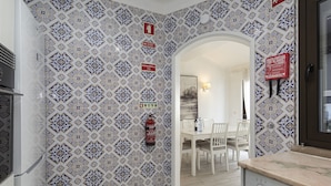 A kitchen with patterned tile walls, a Bosch dishwasher, and a dining area with a white table and chairs. - Vilamoura House Garden by Hopstays | Marina view (Vilamoura)