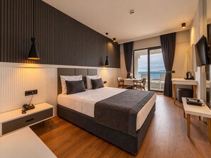 A modern hotel room with a large bed, a desk, and a view of the sea. - Tema 242 Hotel (Antalya)