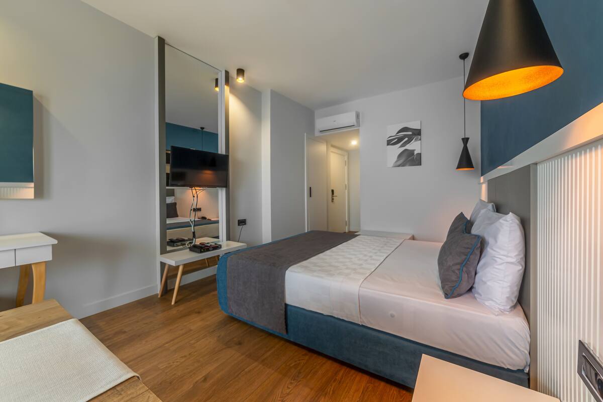 A modern bedroom with a bed, bedside table, and a desk with a chair.