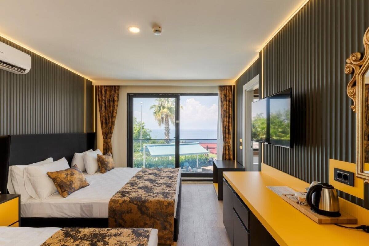 A hotel room with a bed, a desk, a television, and a view of the outdoors.