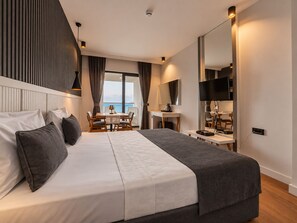 A modern hotel room with a large bed, a desk, a television, and a view of the sea. - Tema 242 Hotel (Antalya)