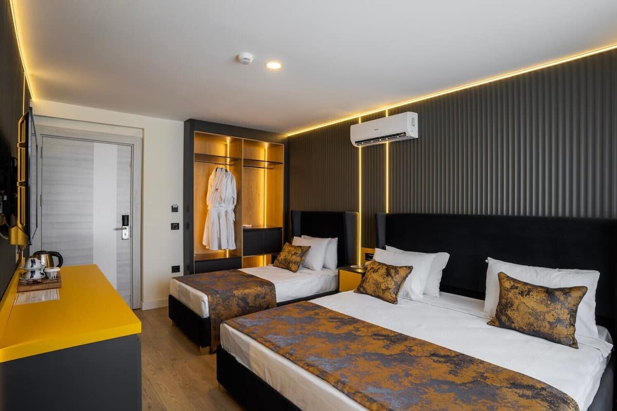 A hotel room with two beds, a minibar, a robe rack, and a modern design.