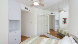 A bedroom with a bed, a wardrobe, a mirror, and a ceiling fan.