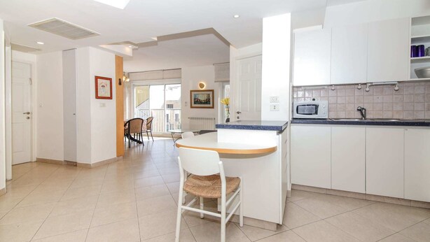 A modern kitchen with a central island, white cabinetry, and a tiled floor.