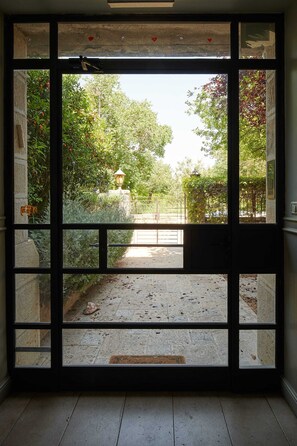 Visão através de uma porta de vidro para uma área externa com caminho, vegetação e um poste de luz.