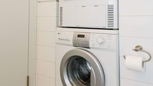 Un espace buanderie compact comprenant un lave-linge à chargement frontal et un sèche-linge superposé.