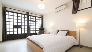 Une chambre d’hôtel avec un grand lit, une chaise, un bureau et une fenêtre avec des rideaux.