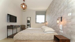 Ein Schlafzimmer mit einem großen Bett, einem Fernseher, einem Schreibtisch und einem Spiegel.