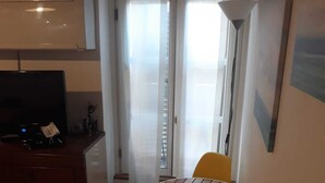 Un pequeño comedor con una mesa redonda y cuatro sillas amarillas. A la izquierda, un televisor sobre un mueble de madera.