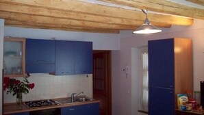 Cocina con armarios azules, techo de madera y lámpara colgante.