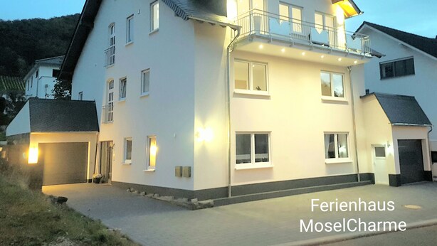 A two-story house with a balcony, multiple windows, and a garage. - Ferienhaus Moselcharme "moselblick" (Alken)