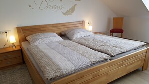 A bedroom with a wooden bed, two bedside tables with lamps, a red chair, and a wall decal that reads "Sweet Dreams". - Ferienhaus Moselcharme "moselblick" (Alken)