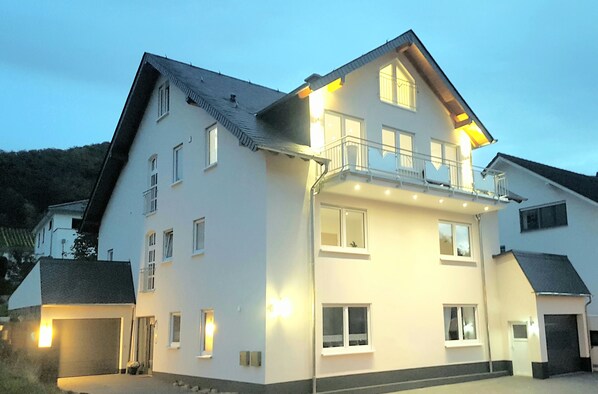 Een twee verdiepingen tellend huis met een balkon, meerdere ramen en een garage.