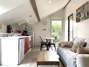 A compact living space with a kitchenette, a dining area, and a sofa with cushions. - Apartment TANGARA with balcony (Lagnieu)