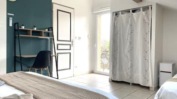 A bedroom with a bed, a chair, a shelf, a door, and a view of the outside.