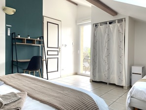 A bedroom with a bed, a chair, a shelf, a door, and a view of the outside. - Apartment TANGARA with balcony (Lagnieu)