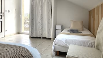 A bedroom with a bed, a bedside table, a chair, a window with a curtain, and a view of the outside.