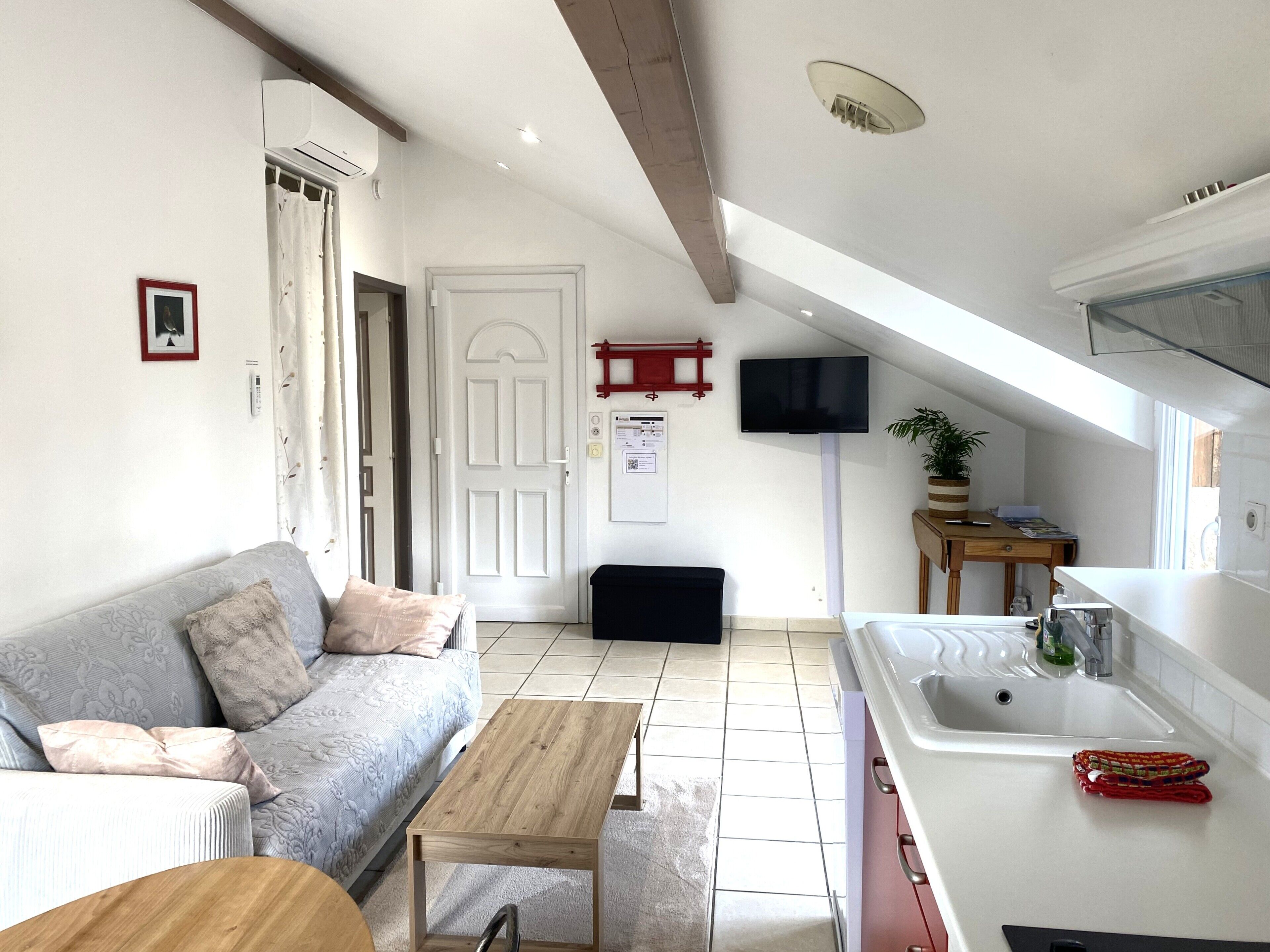 A modern apartment with a living room, kitchenette, and a small dining area.