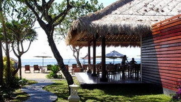 A beachside resort with a thatched-roof structure, outdoor seating, and a pathway leading to the beach. - Puri Benoa Suites Bungalows (Nusa Dua)