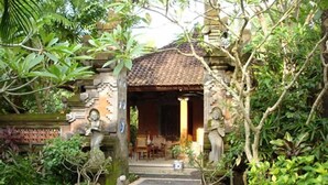 A traditional stone structure with a tiled roof, surrounded by lush greenery and potted plants. - Puri Benoa Suites Bungalows (Nusa Dua)