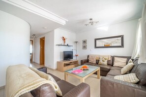 Een woonkamer met een bank, een salontafel, een televisie en een spiegel.