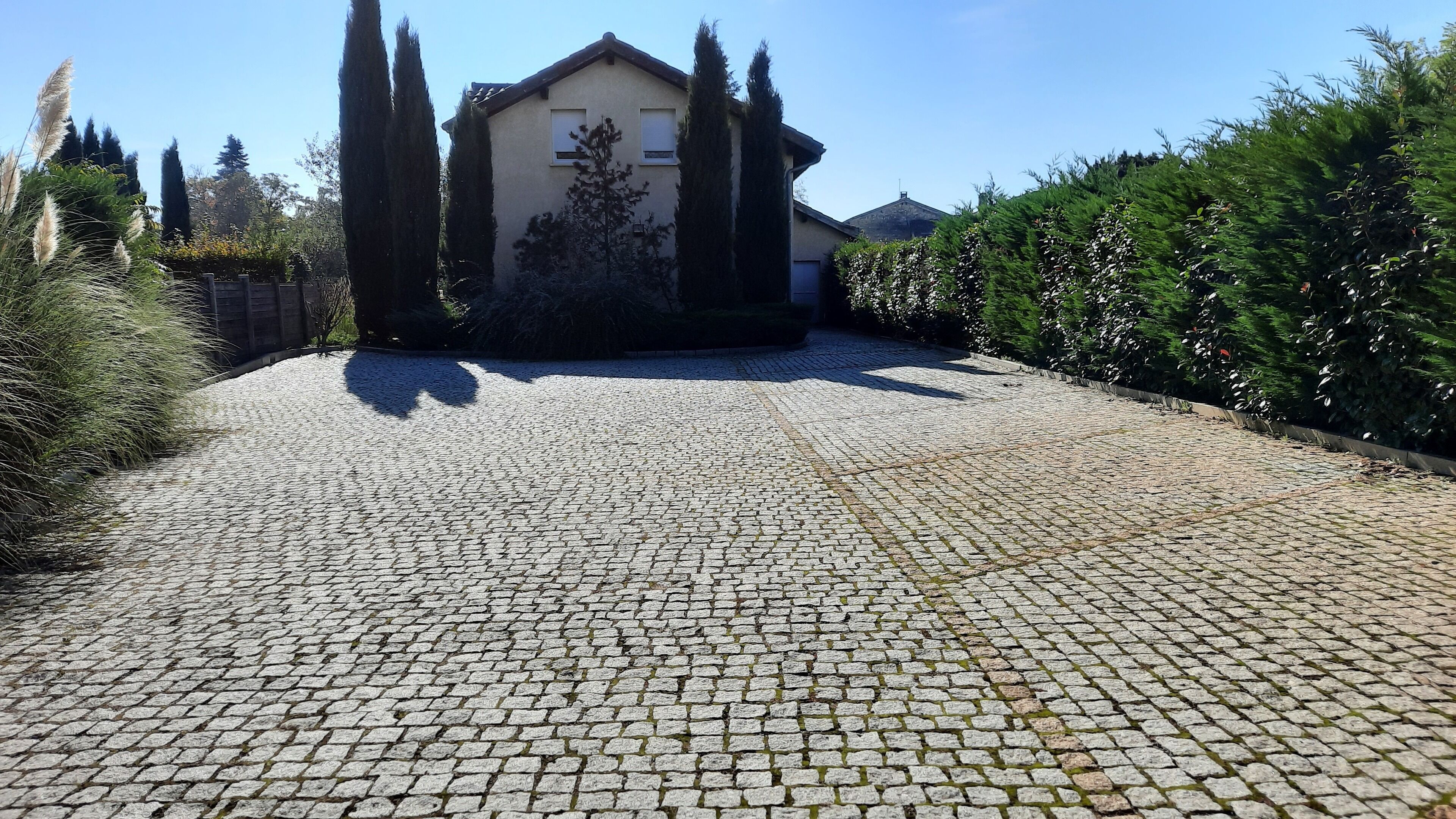 Um caminho de pedras irregulares leva a um edifício com fachada bege e telhado inclinado.