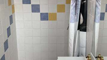 Ein Badezimmer mit gefliestem Duschbereich, einem Waschbecken mit Wasserhahn und einer Duschvorhang.