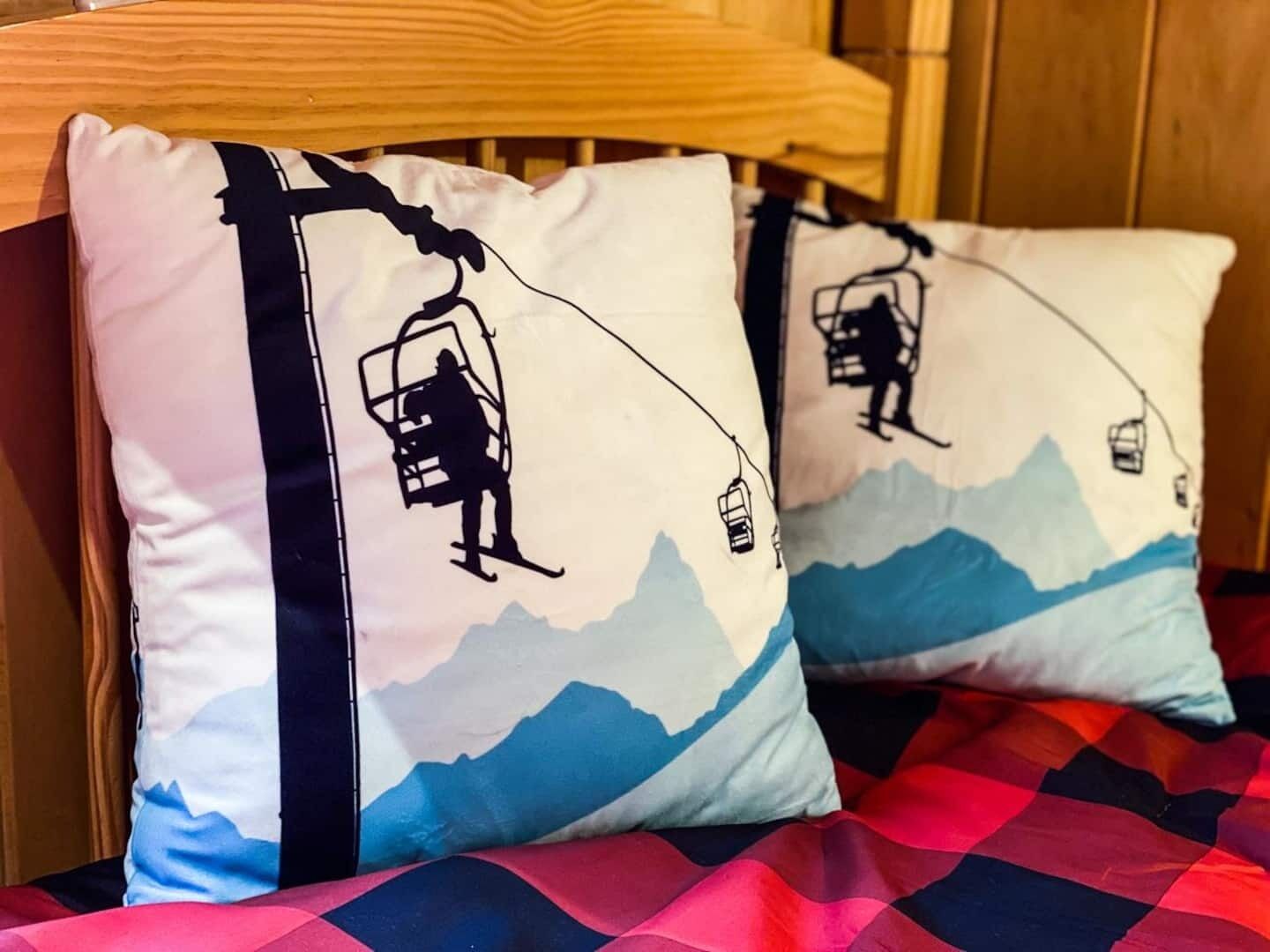 Een bed met een geruit sprei en twee kussens met een ontwerp van een skilift.