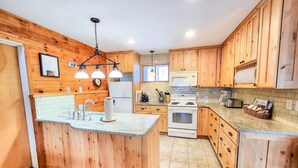 Une cuisine avec des meubles en bois, un îlot central, un four à micro-ondes, une cuisinière et un évier.