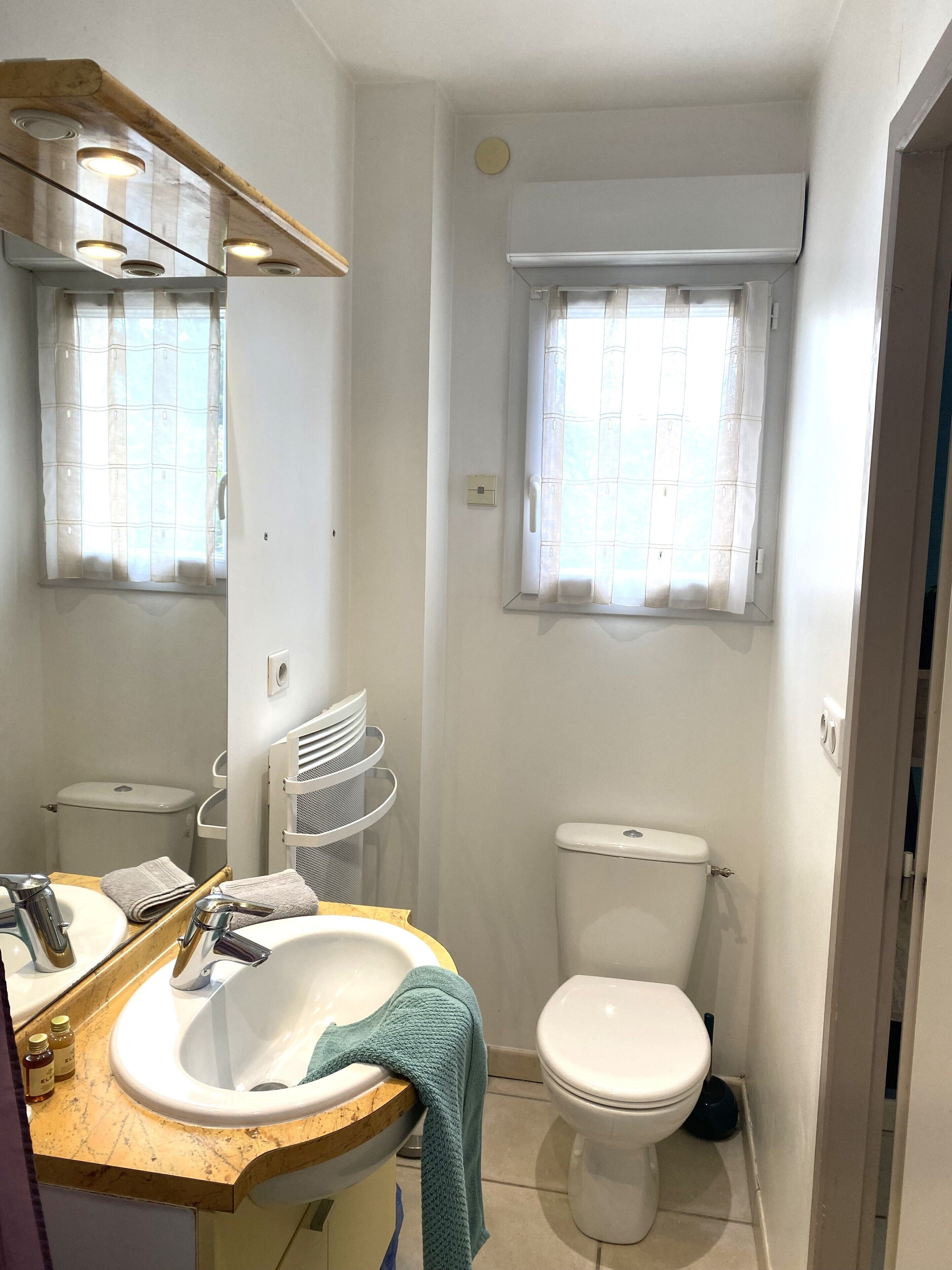 A compact bathroom with a sink, mirror, and toilet.