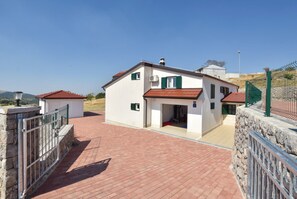 A two-story house with a red-tiled roof, a paved driveway, and a stone wall. - Luxury Mountain Villa W.heated Pool & Largegarden (Muc)