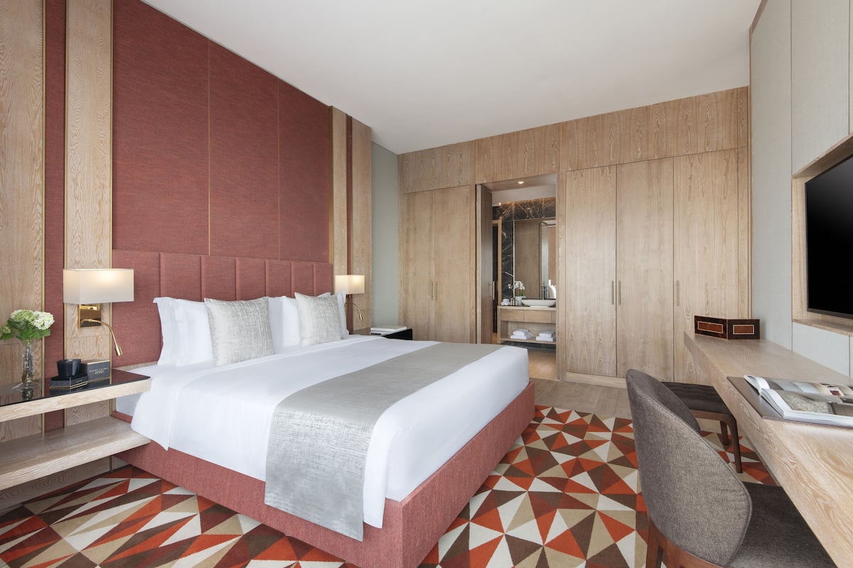 Habitación de hotel con una cama grande, un escritorio y un televisor.