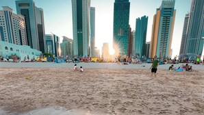 A beach with a city skyline in the background. - The Bentley Luxury Hotel and Suites (Doha)
