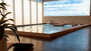 A spacious indoor pool with a large window and a waterfall feature. - The Bentley Luxury Hotel and Suites (Doha)