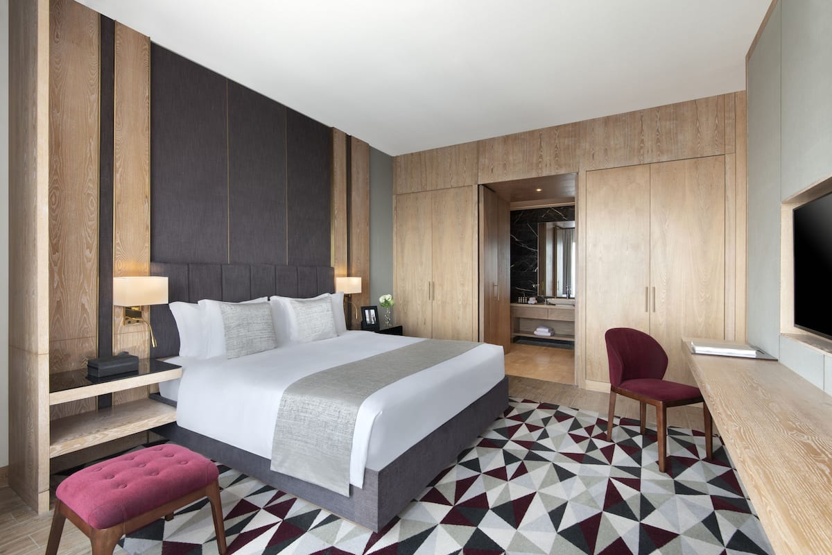 Una habitación de hotel moderna con una cama grande, un escritorio, una silla y un televisor.