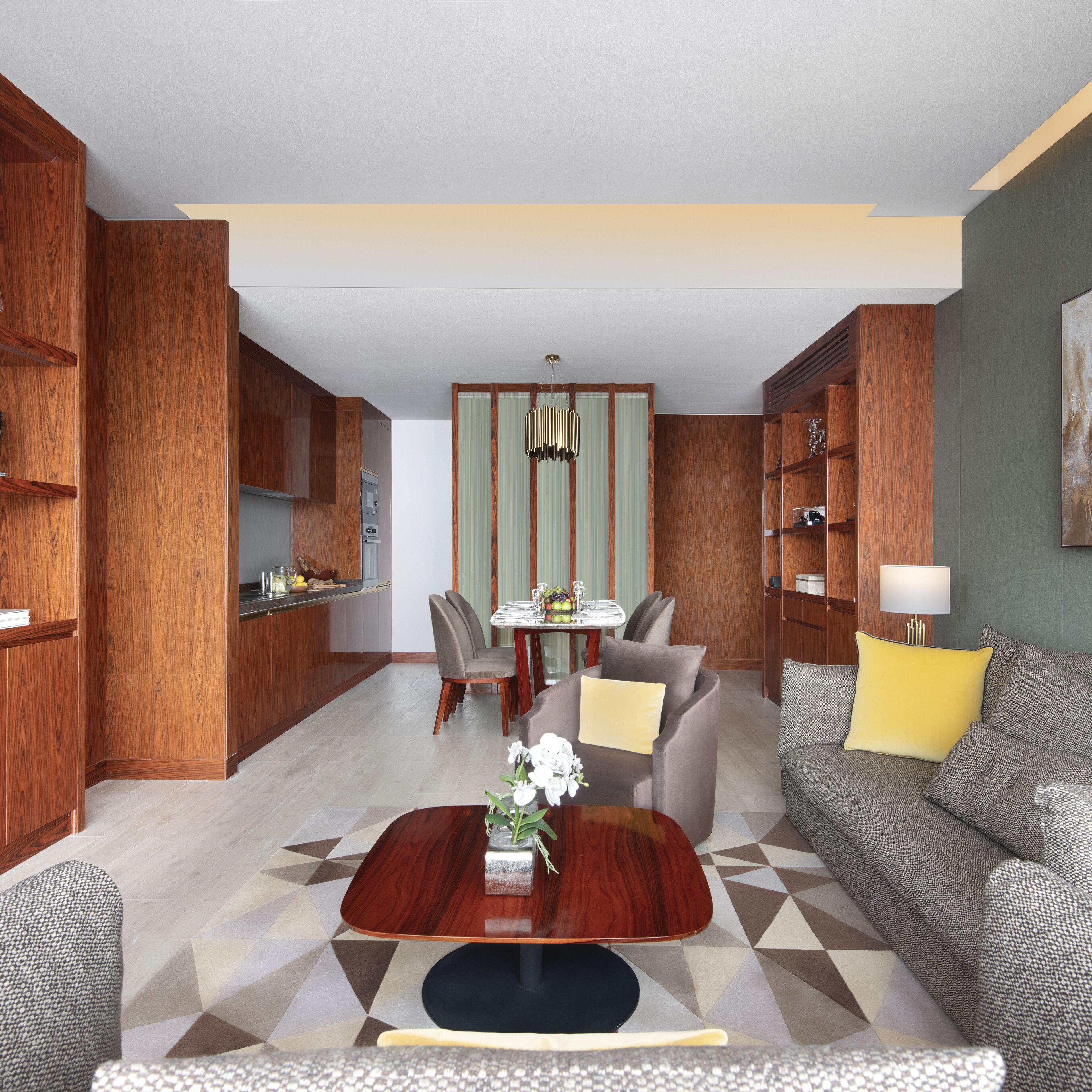 A modern living room with a dining area, wooden cabinetry, and a geometric patterned floor.