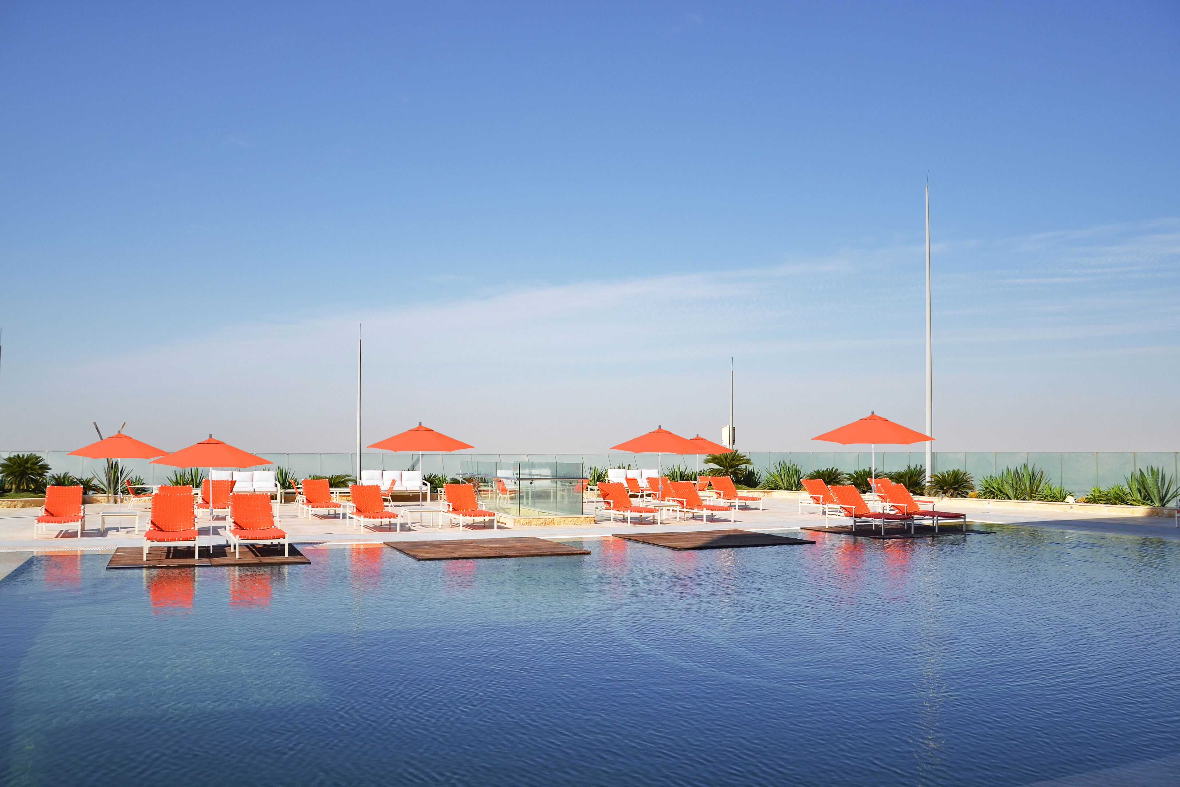 Una piscina al aire libre, sombrillas, sillones reclinables de piscina