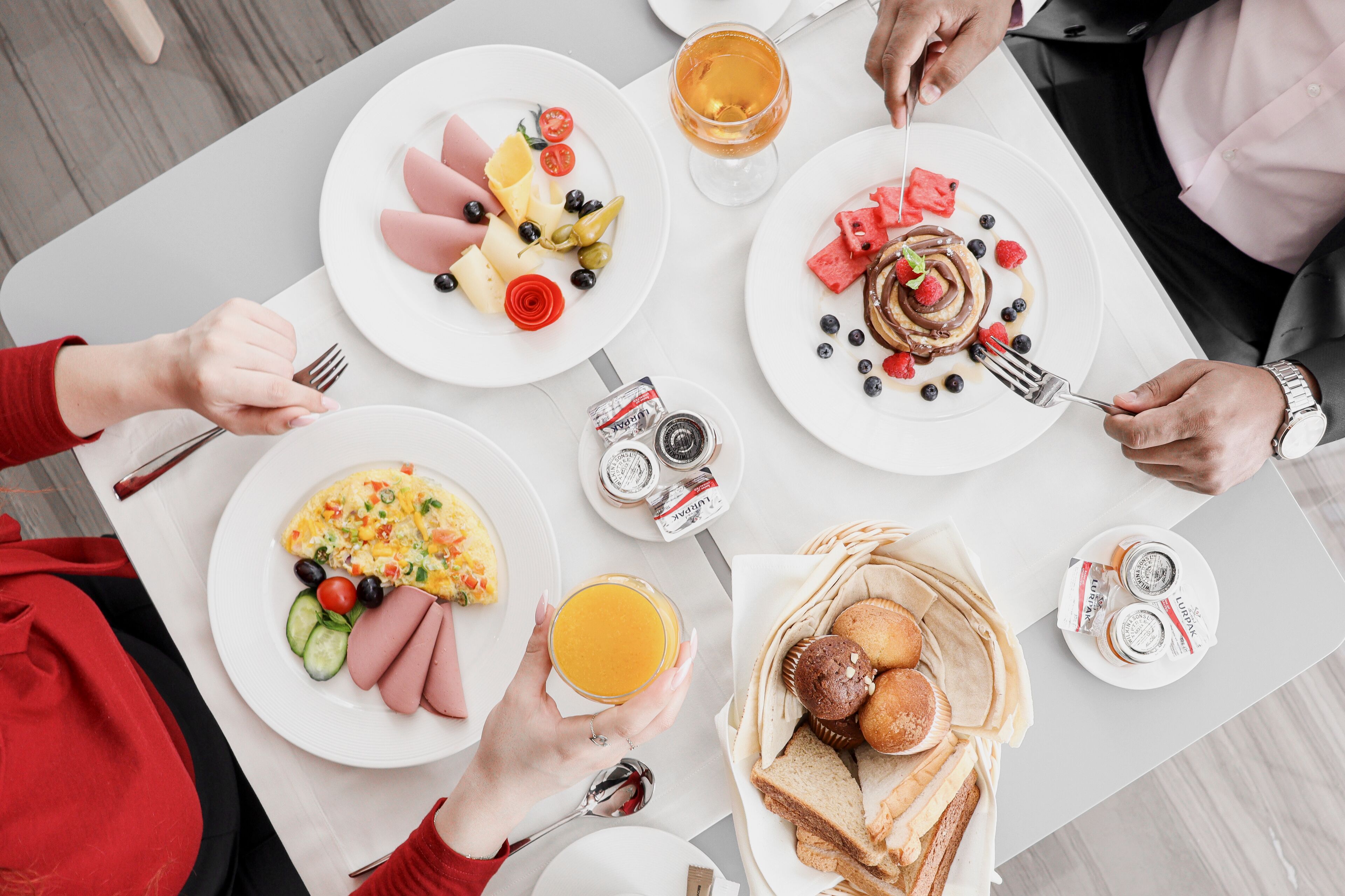 A breakfast setting with various dishes, including eggs, sausages, and toast, on a white table.
