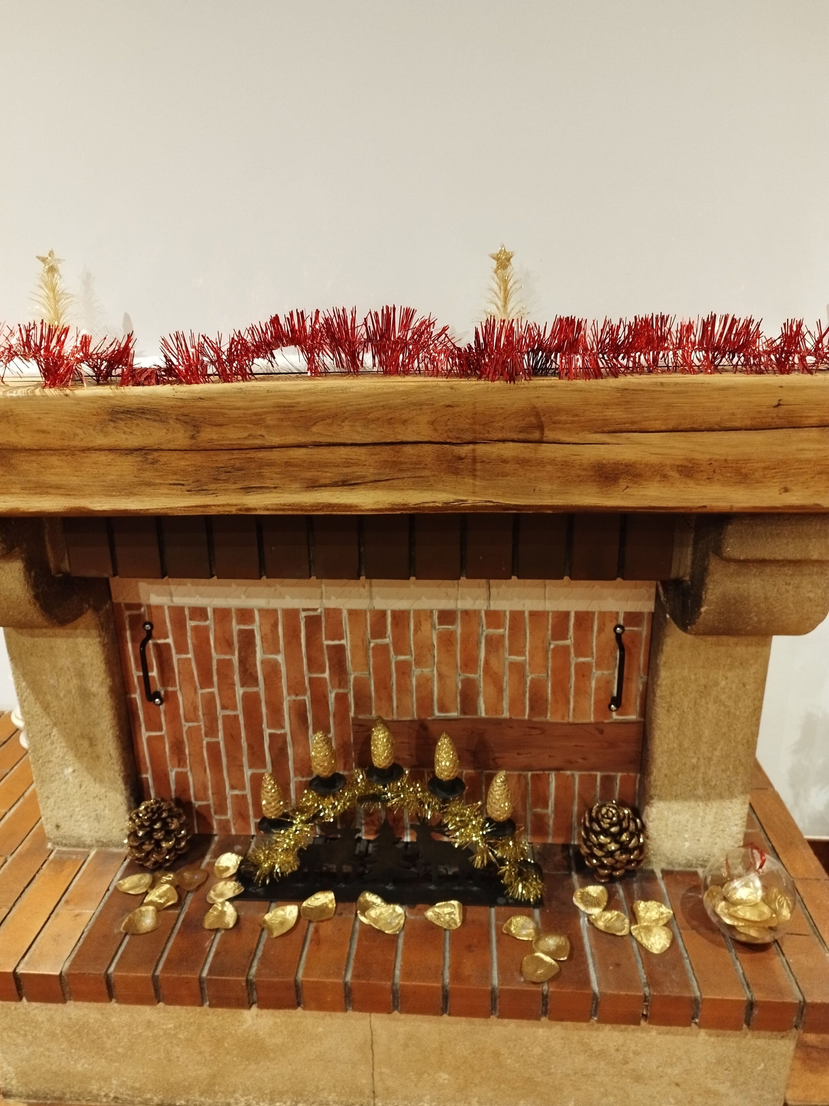 Une cheminée avec un manteau en briques, des décorations dorées et des guirlandes rouges.