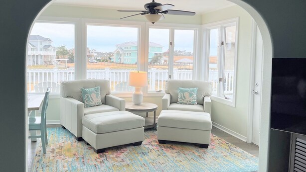 Une pièce chaleureuse avec deux fauteuils blancs, une petite table ronde et un tapis coloré.