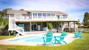 Une maison à deux étages dotée d’un balcon, d’une piscine et d’un espace salon extérieur.