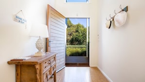 Een hal met een houten dressoir, een lamp en een bord waarop staat 'GONE FOR A DIP'.