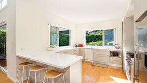 Een moderne keuken met een groot eiland, barstoelen en uitzicht op groen.