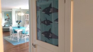 A room with a dining area featuring a table with chairs, a vase with flowers, and a painting of a pelican on the wall. - Beach and river view cottage with deck and specatuclar views. (Matagorda)