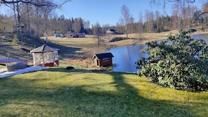 A lakeside property with a gazebo, a small shed, and a fenced area. - Charming 2-bed House at the Lake Close Gustavsfors (Gustavsfors)
