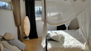 A bedroom with a canopy bed, a bedside lamp, and a view of trees through a window. - Charming 2-bed House at the Lake Close Gustavsfors (Gustavsfors)