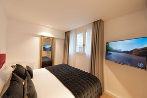 Une chambre d’hôtel avec un lit, une télévision, une fenêtre et un miroir.