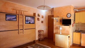 A compact kitchen with wooden cabinets, a built-in stove, and a small sink. - Maison des skieur- ski out (Sestriere)