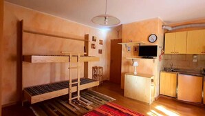 A compact kitchen with wooden cabinets, a built-in stove, and a small countertop. - Maison des skieur- ski out (Sestriere)